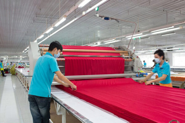 Công nhân trải vải để chuẩn bị cắt khi sản xuất áo thun